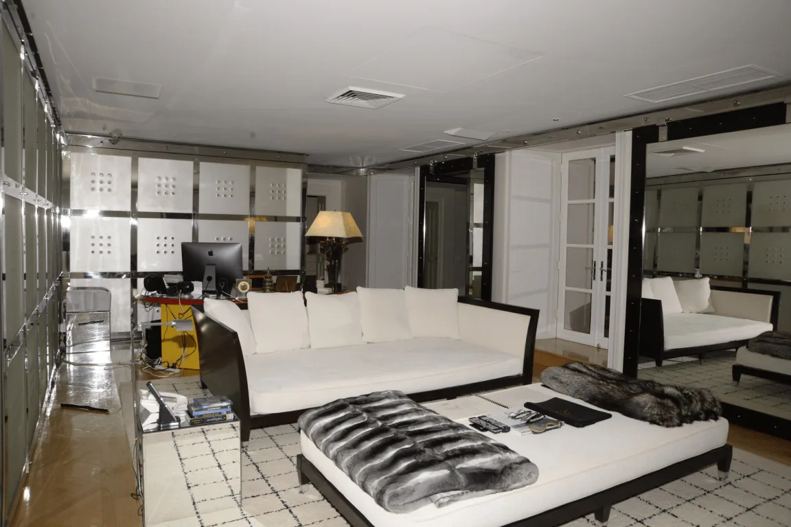 Moderne woonkamer met witte bank, pluchen poef en spiegelwanden