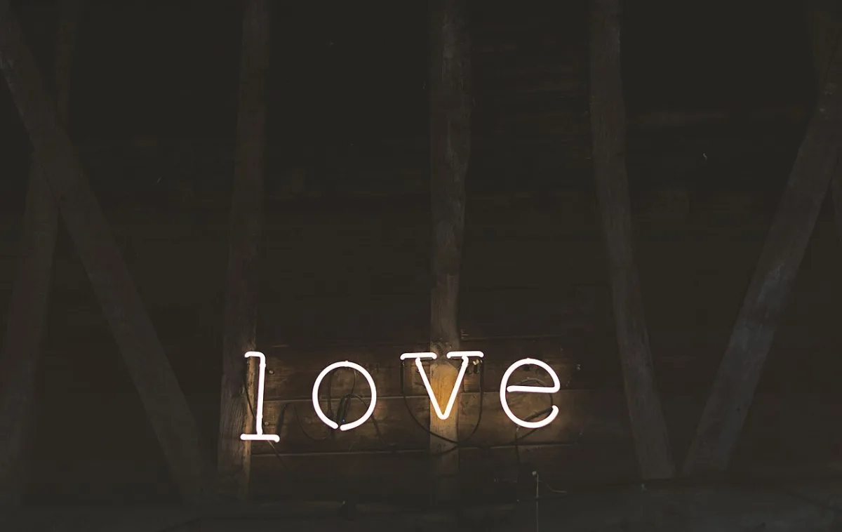 Wit neon lichtwoord 'love' aan een houten wand