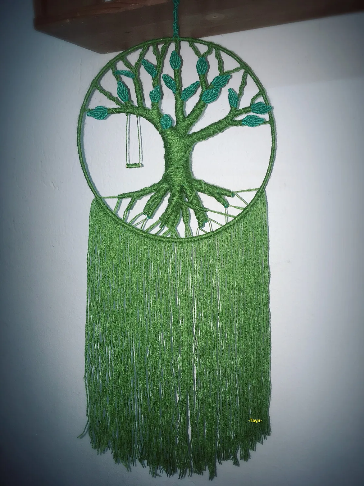 Macramé wandkleed in de vorm van een levensboom met groene franjes